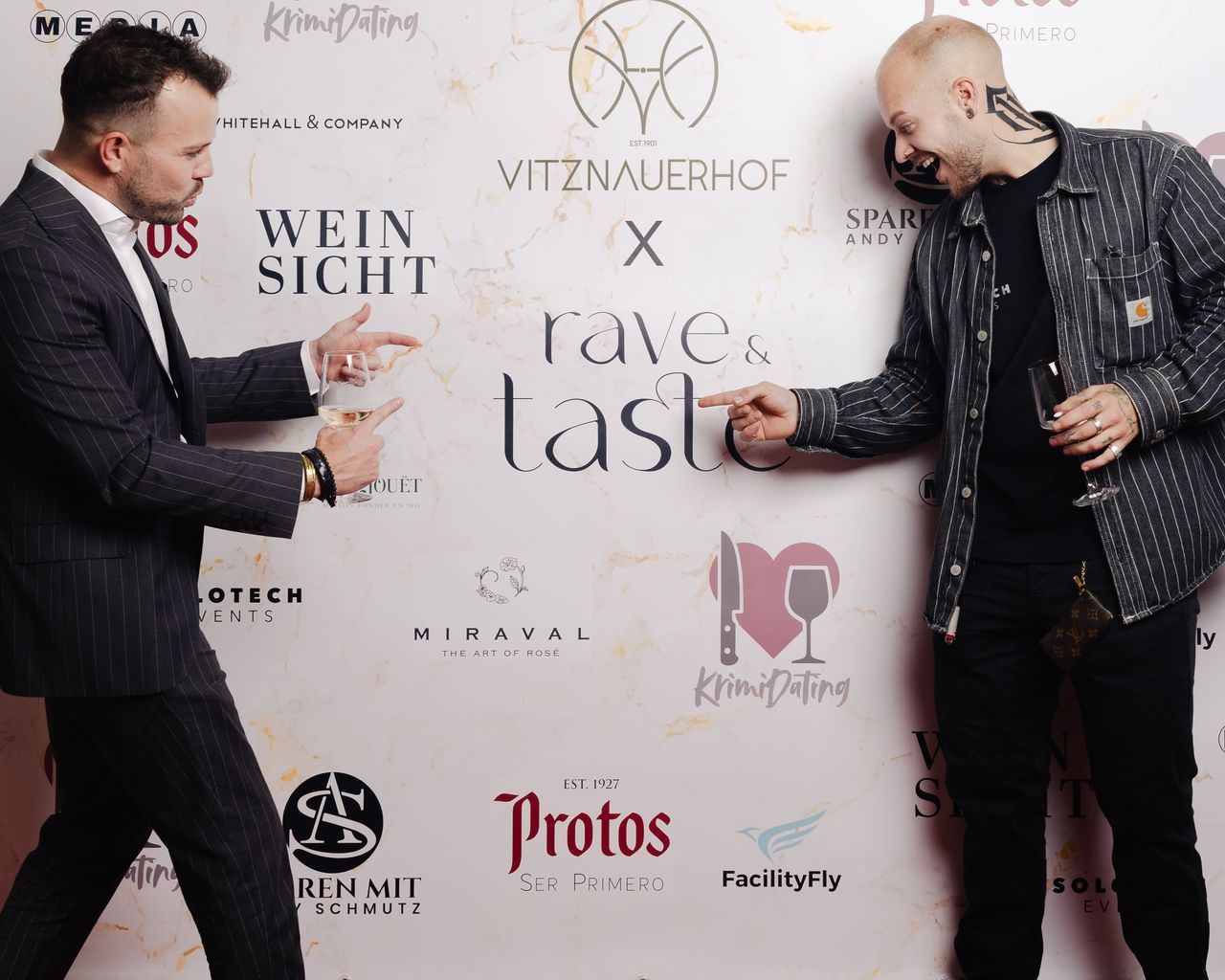 Andreas Schmutz und ein Gast mit Weingläsern vor der Rave & Taste Sponsor-Wand