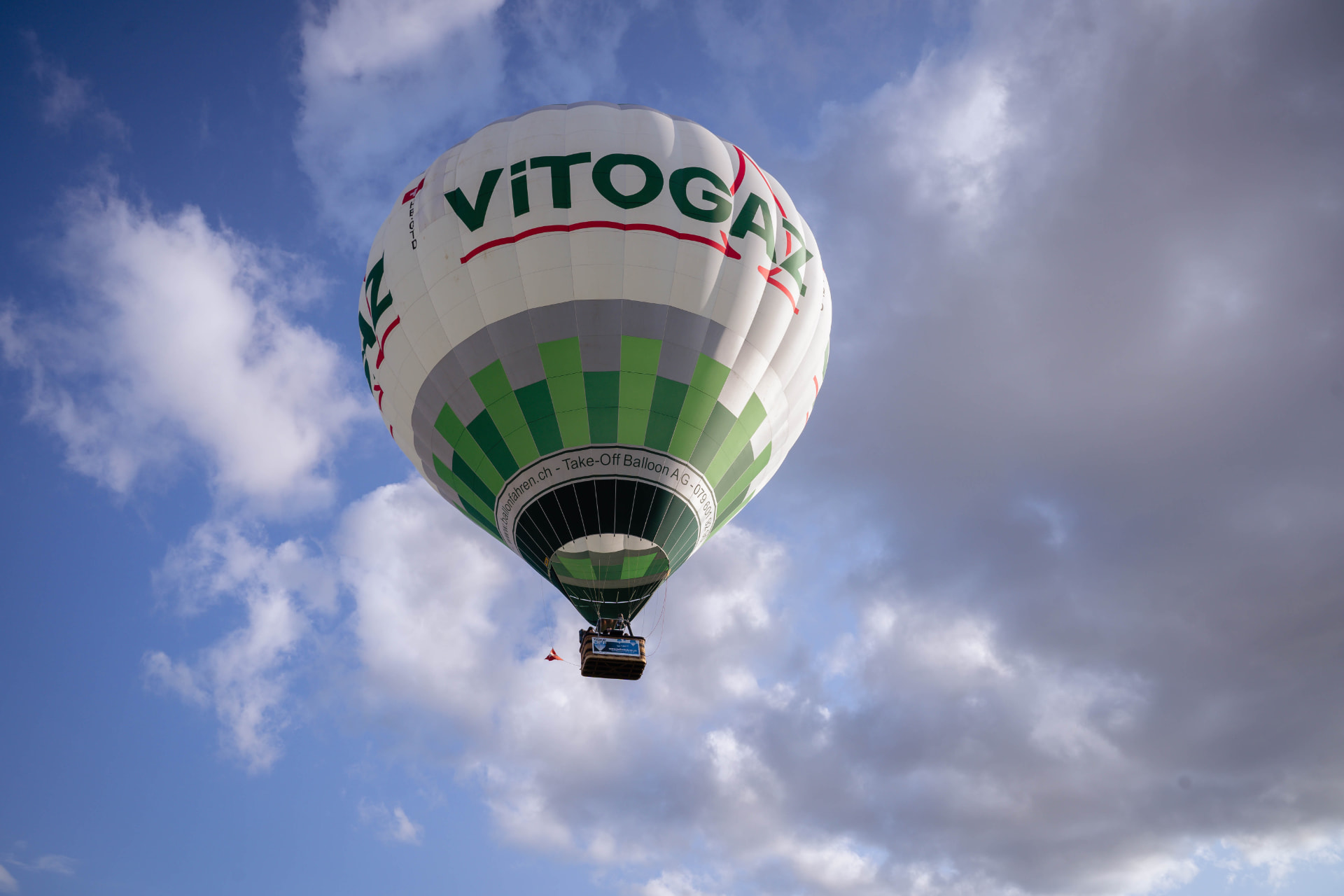 Heissluftballon mit Gästen im Korb vor blauem Himmel