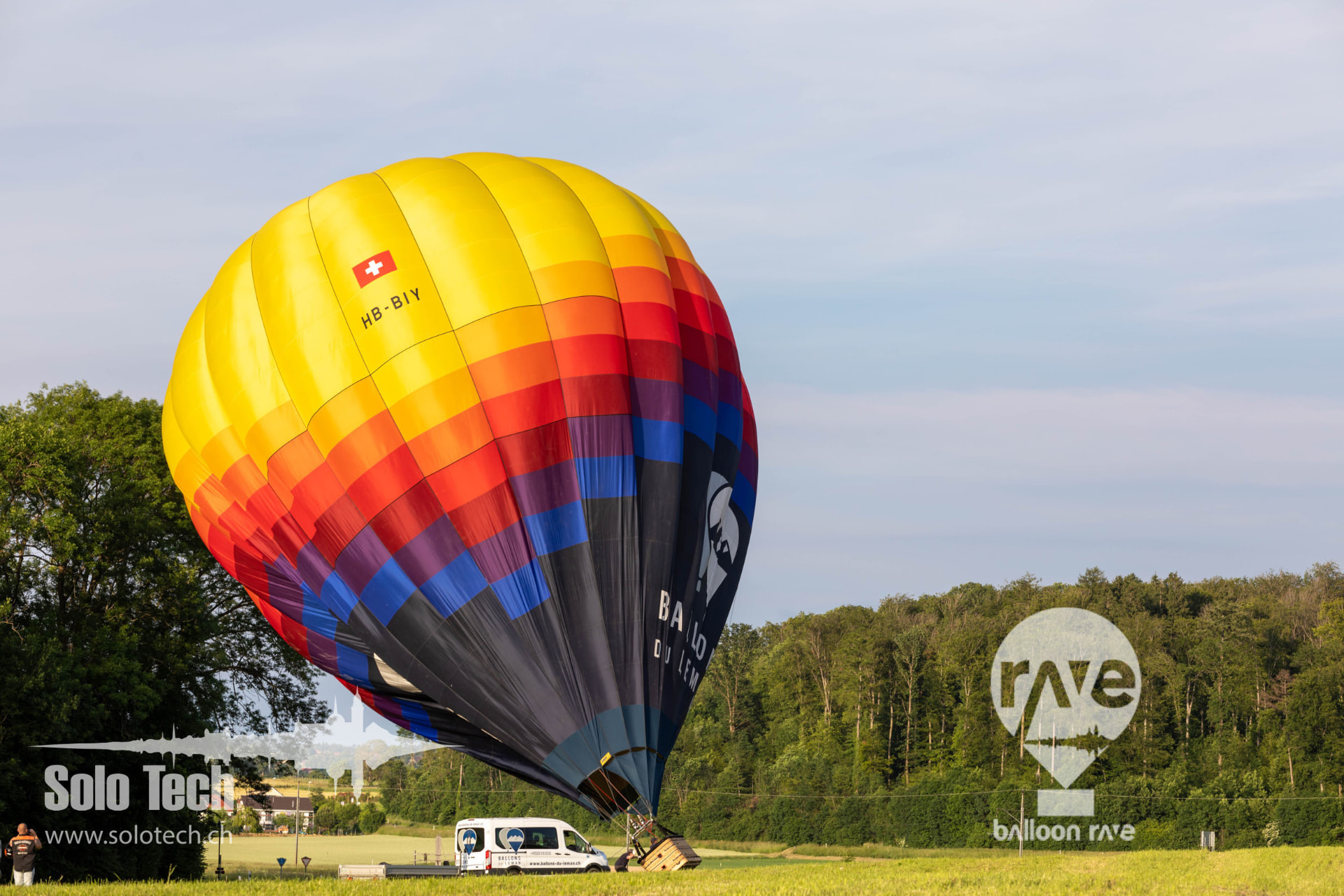 Heissluftballon mit Schweizerkreuz beim Aufblasen auf der Wiese